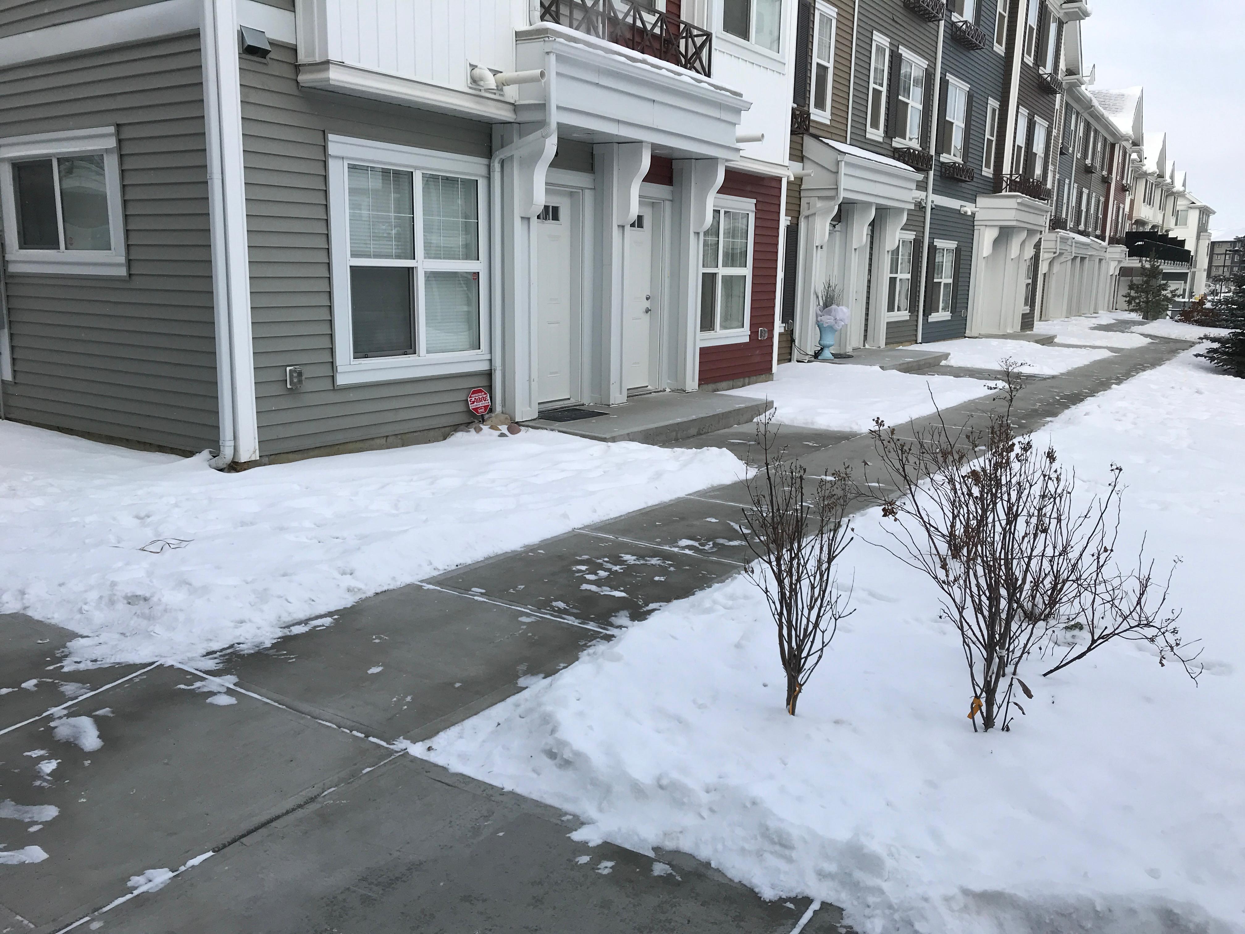 Row of townhouses with snow-cleared front sidewalks and driveways